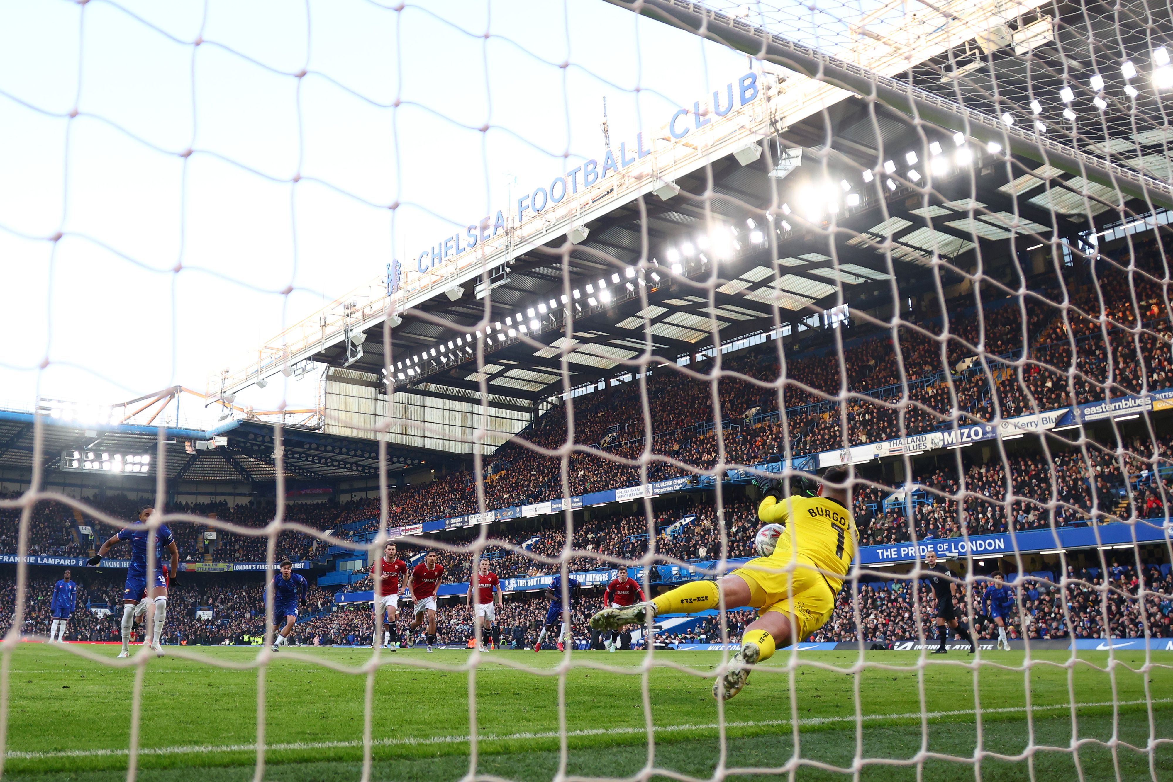 Harry Burgoyne of Morecambe saves a penalty taken by Christopher Nkunku of Chelsea.