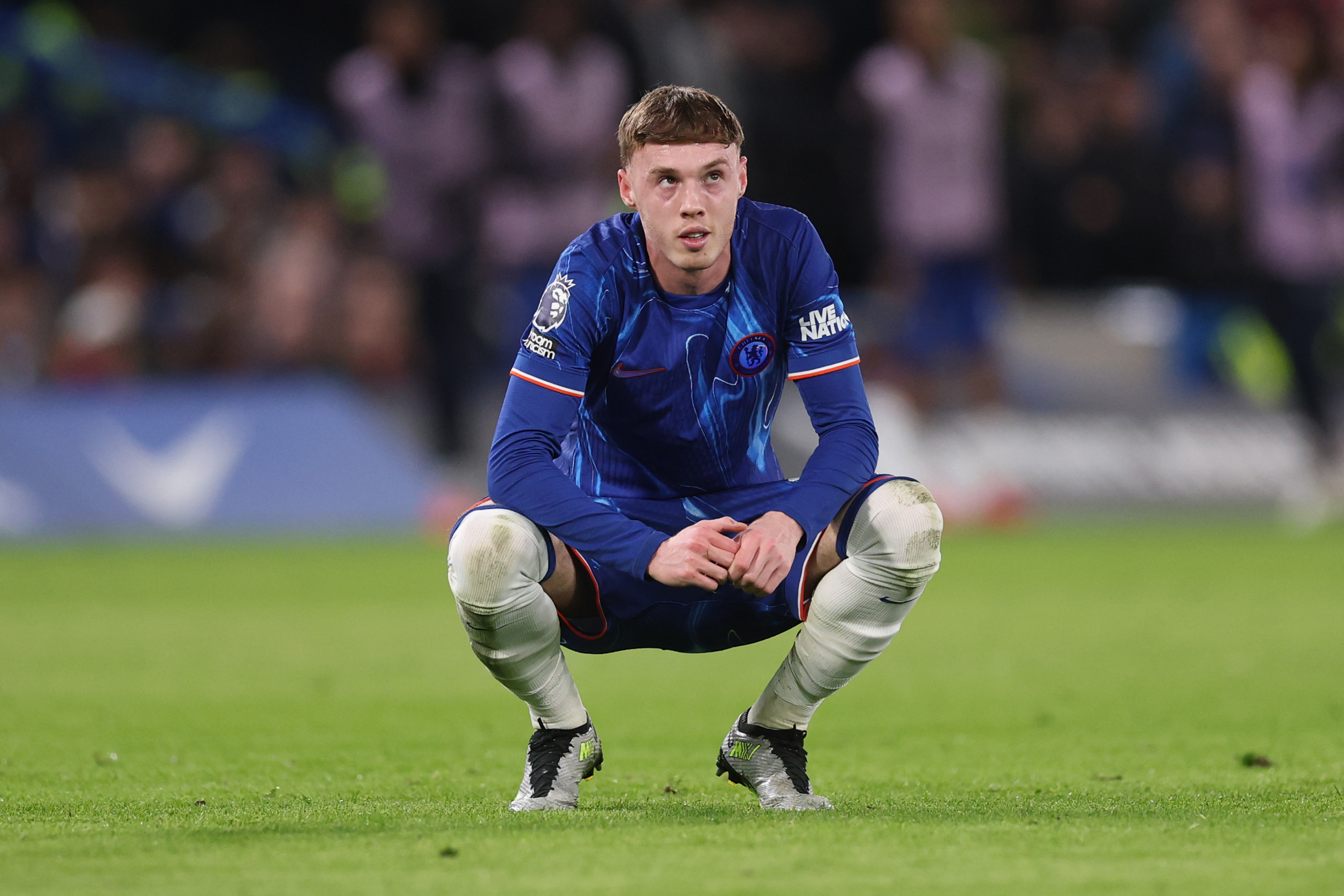 Cole Palmer of Chelsea looks on while hunched on the ground