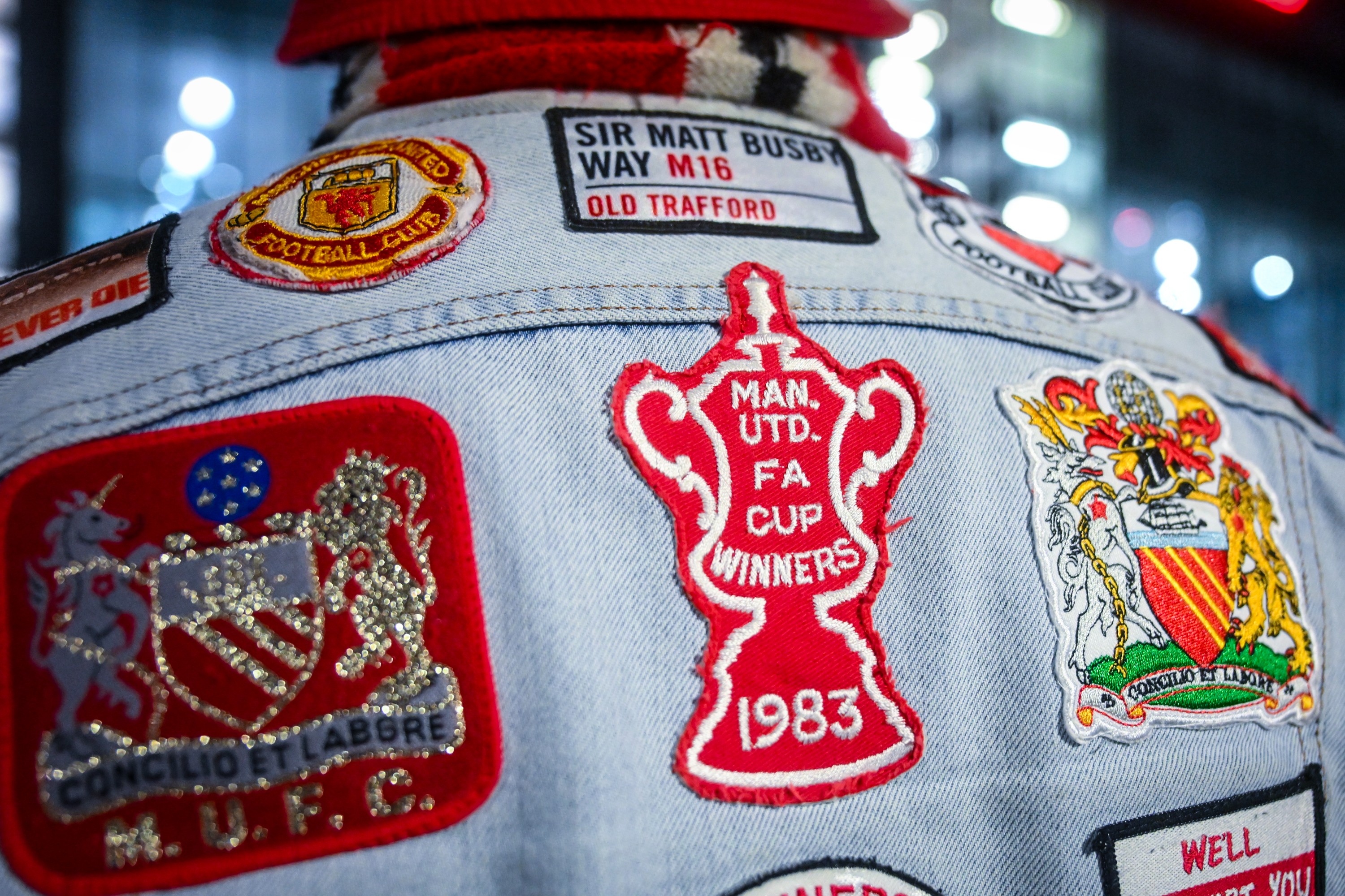 A Manchester United fan poses in his custom made denim jacket
