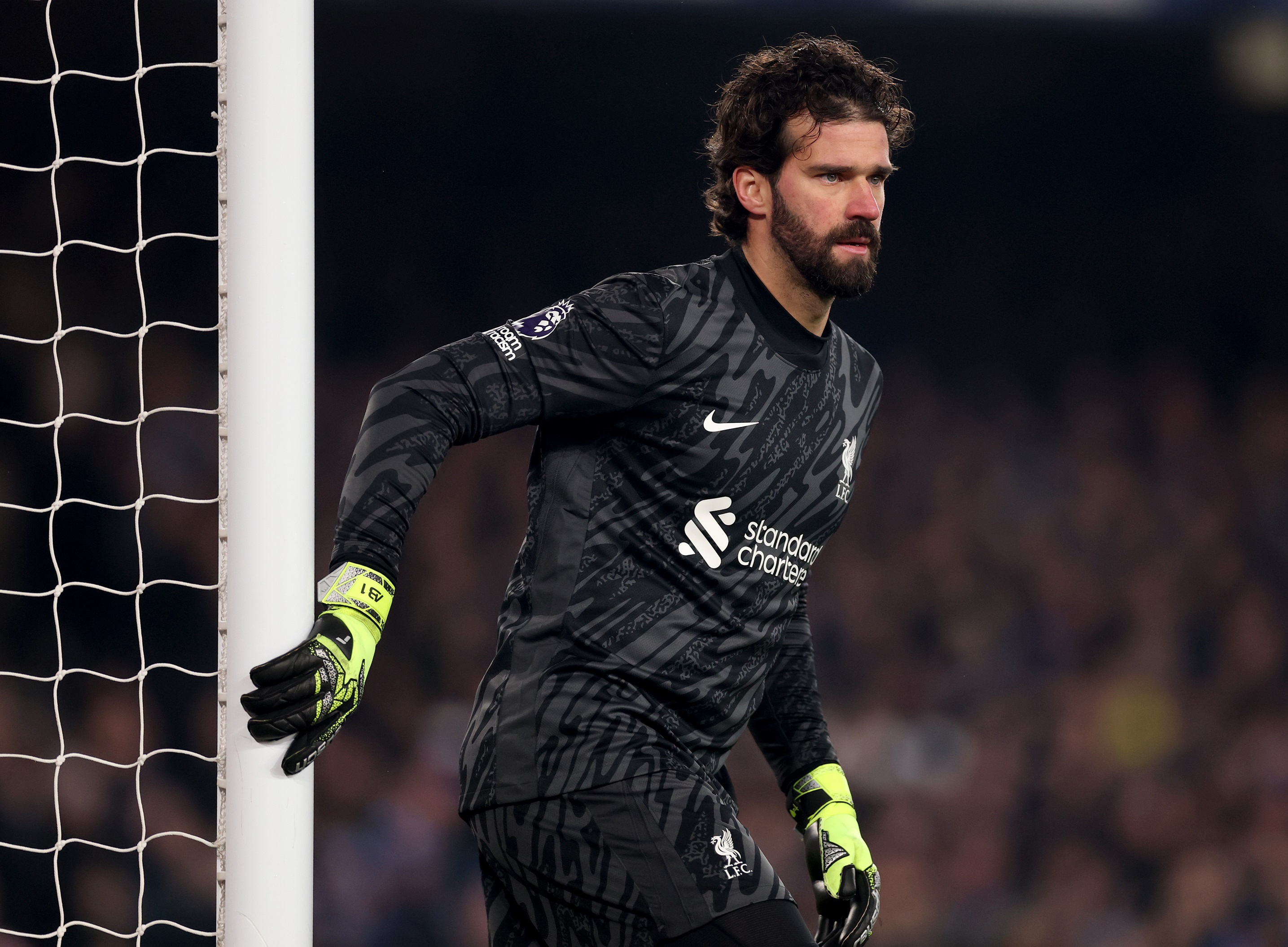 Liverpool goalkeeper Alisson Becker holds on to one goal post.