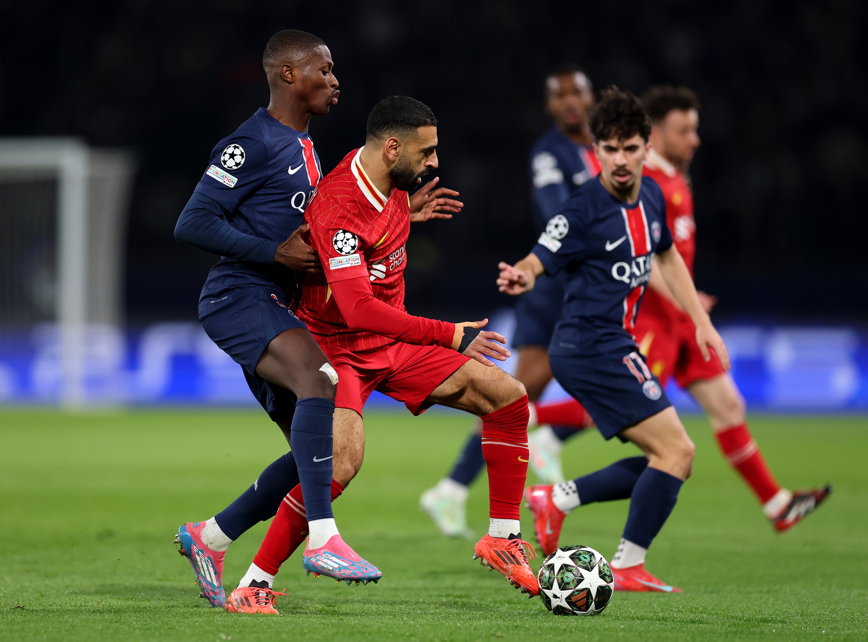 Mo Salah dribbles with the ball against PSG players.