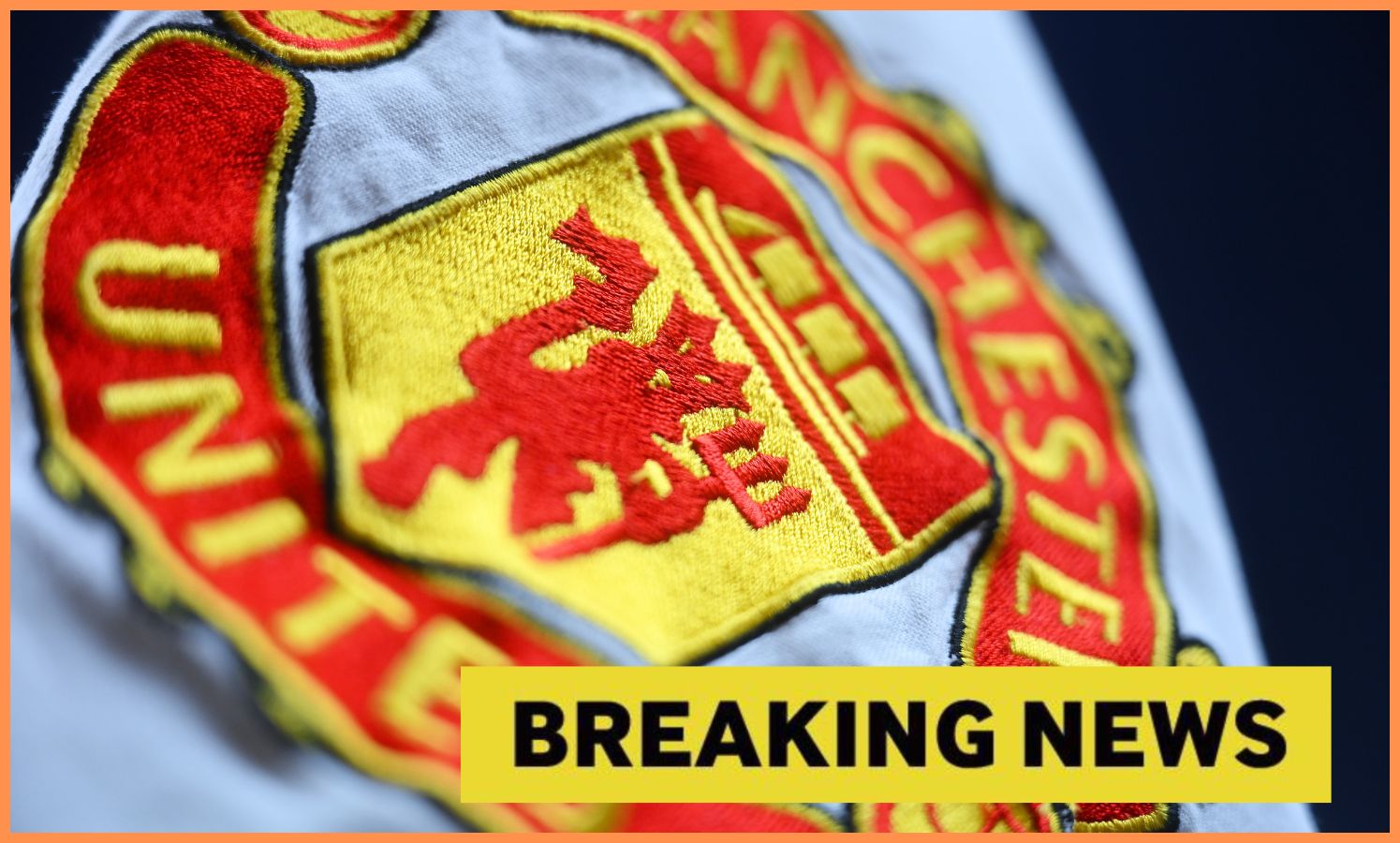 Close-up image of Manchester United logo with yellow breaking news banner