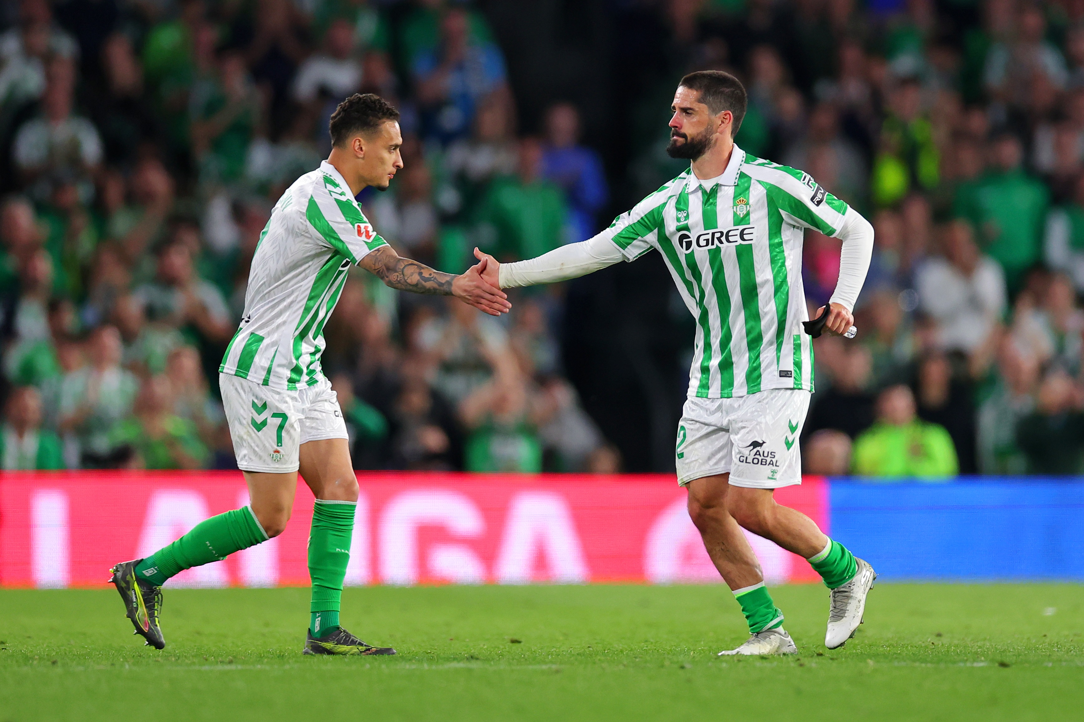 Antony shakes hands with Real Betis teammate Isco on the pitch.