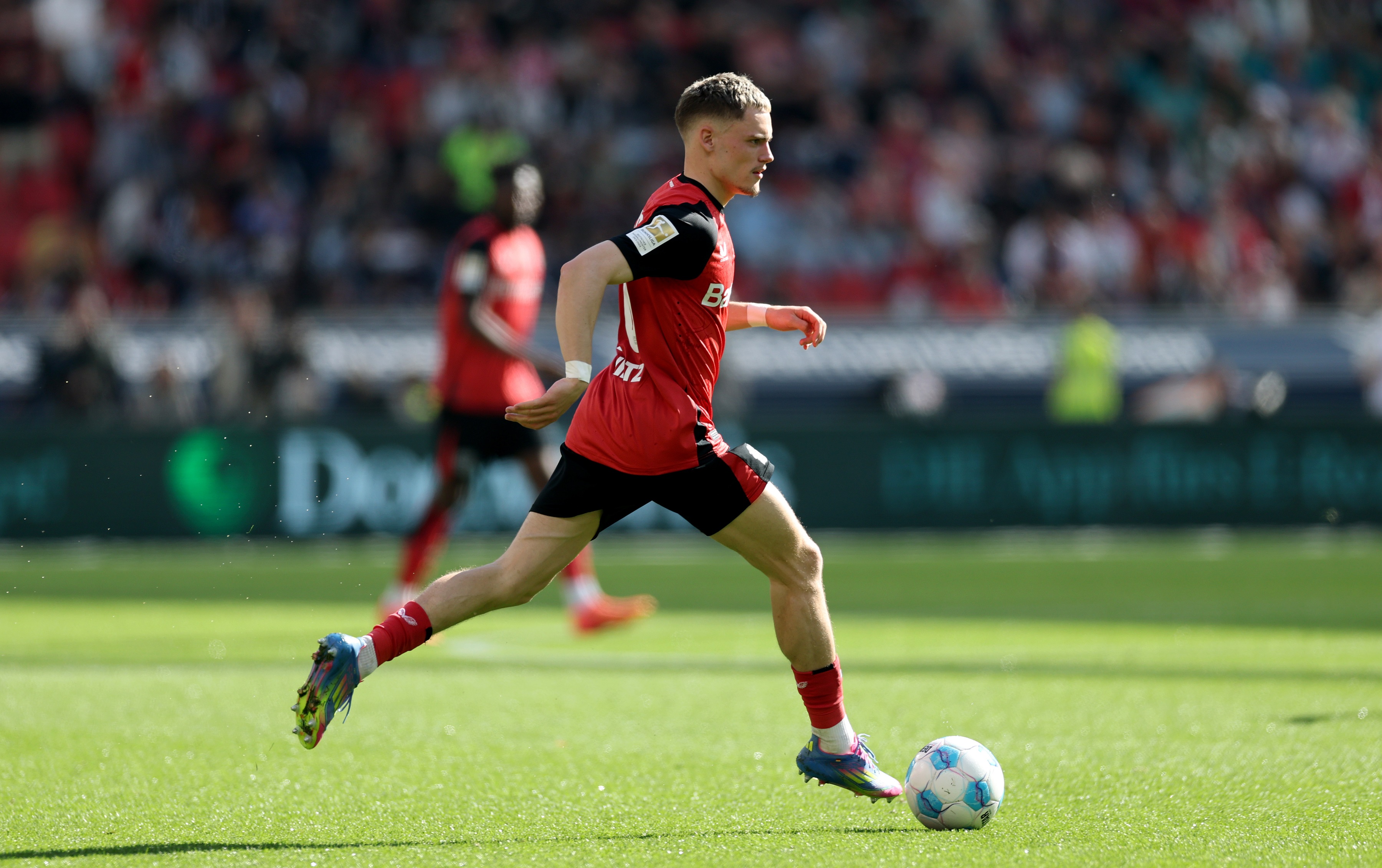 Florian Wirtz dribbles with the ball with one leg trailing.