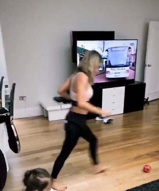 She steps up to strike the ball while her daughter plays on the floor