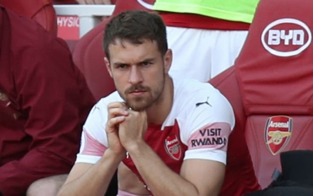 Arsenal (but not for long) midfielder Aaron Ramsey looks serious as he warms the bench