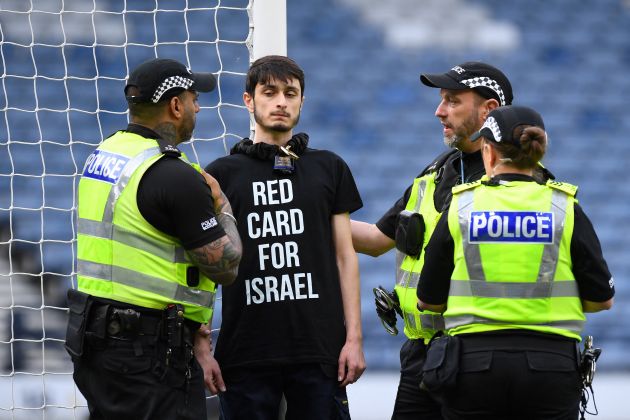A demonstrator wearing a t-shirt reading "Red card for Israel" pictured after chaining himself to a goalpost at Hampden Park