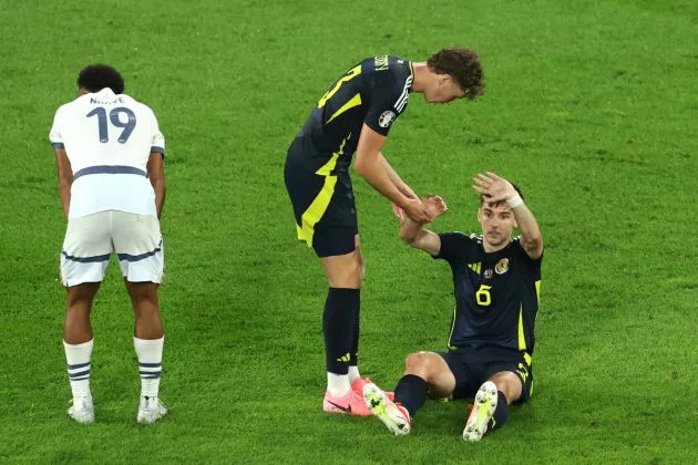 Kieran Tierney of Scotland calls for medical assistance as he interacts with Jack Hendry of Scotland after being challenged by Dan Ndoye of Switzerland during the UEFA EURO 2024 group stage match between Scotland and Switzerland at Cologne Stadium on June 19, 2024