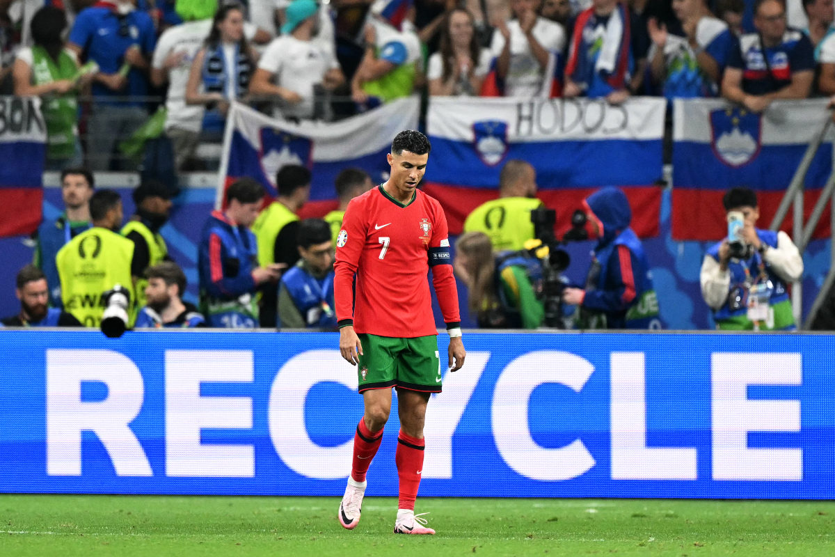 Un tifoso sloveno mostra la maglia di Messi mentre Ronaldo tira una punizione
