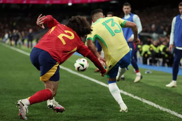 Spain's forward #12 Mato Joselu (L) fights for the ball with Brazil's defender #13 Yan Couto during the international friendly football match between Spain and Brazil at the Santiago Bernabeu stadium in Madrid on March 26, 2024.