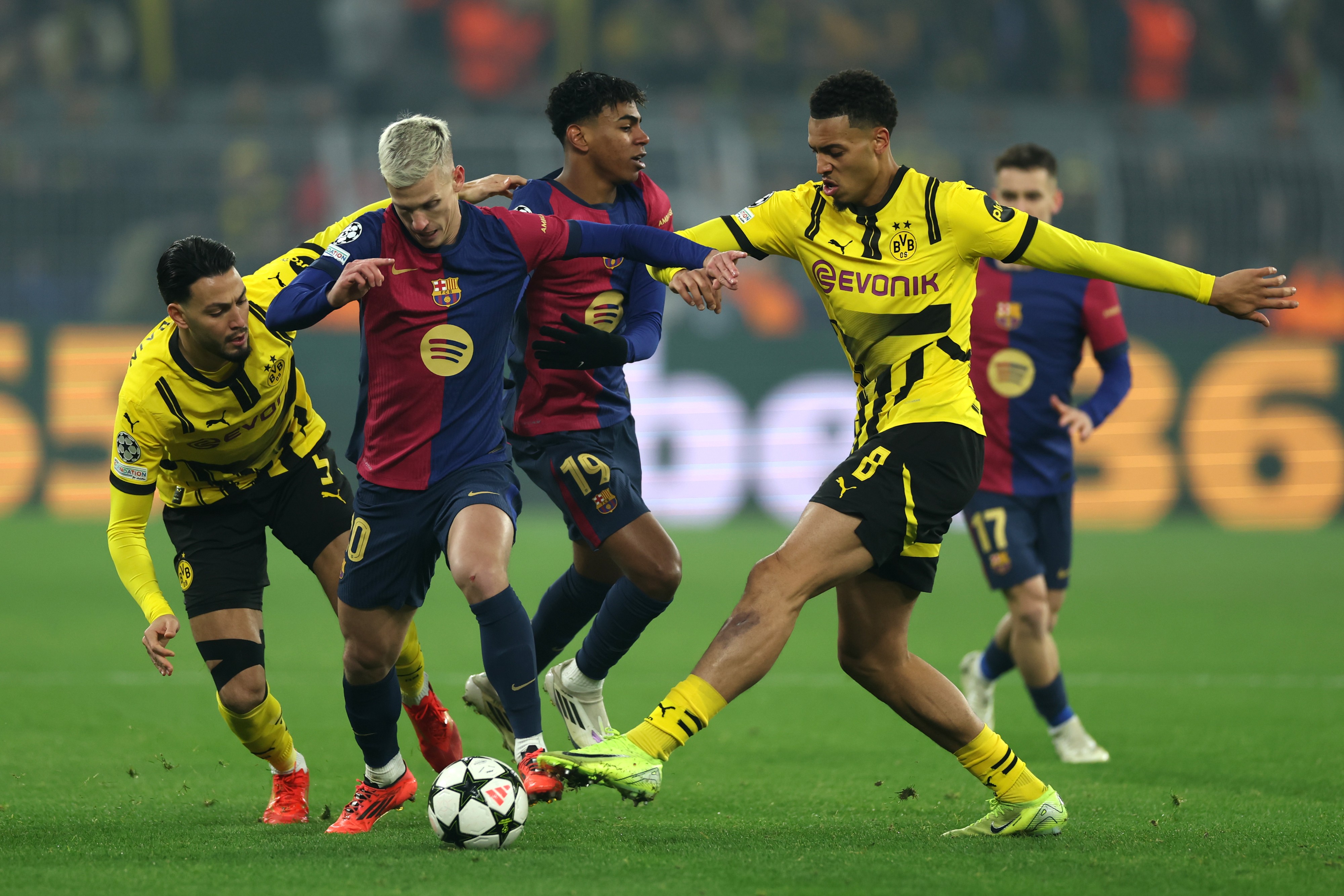 Dani Olmo of FC Barcelona is challenged by Ramy Bensebaini and Felix Nmecha of Borussia Dortmund