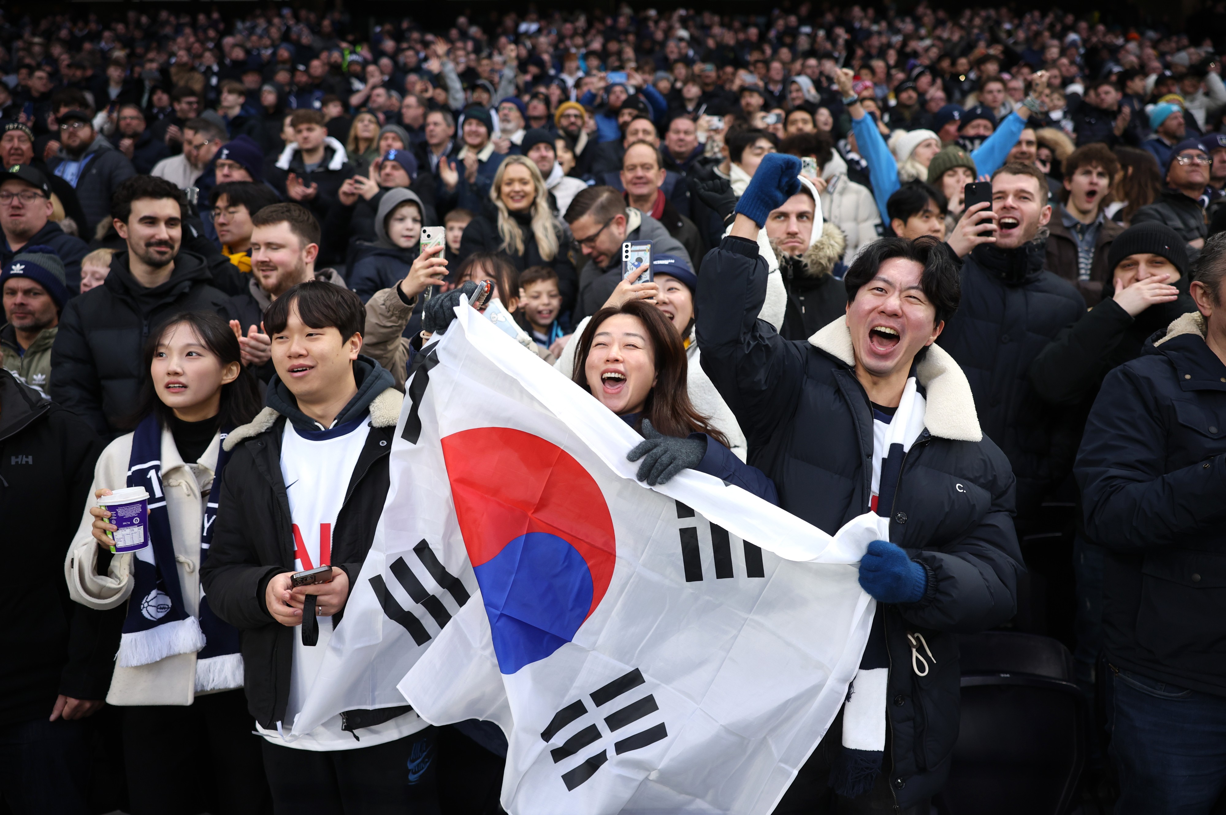 Tottenham fans hold a South Korean flag and cheer for Heung-Min Son