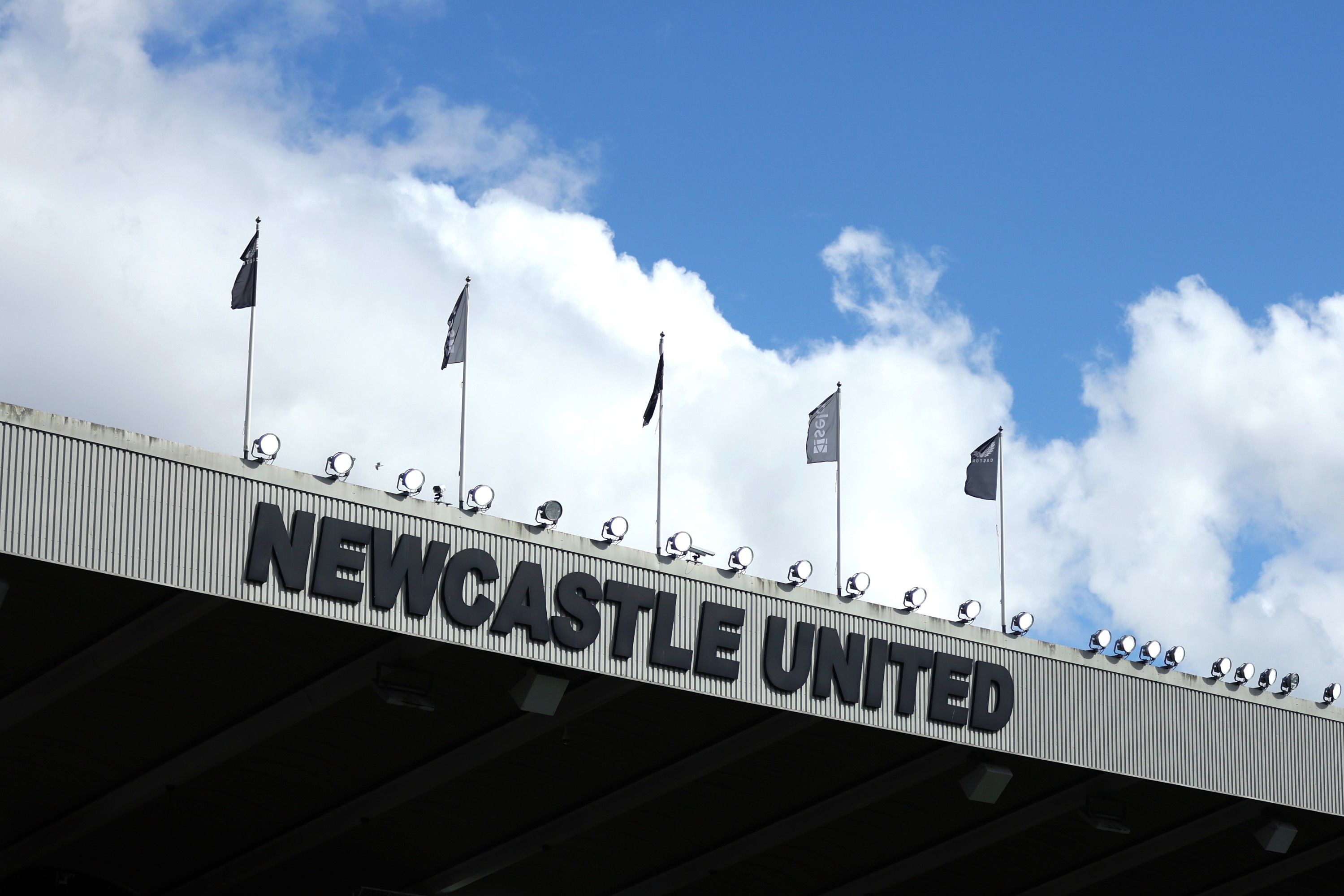 Blue sky appears above the Newcastle United sign