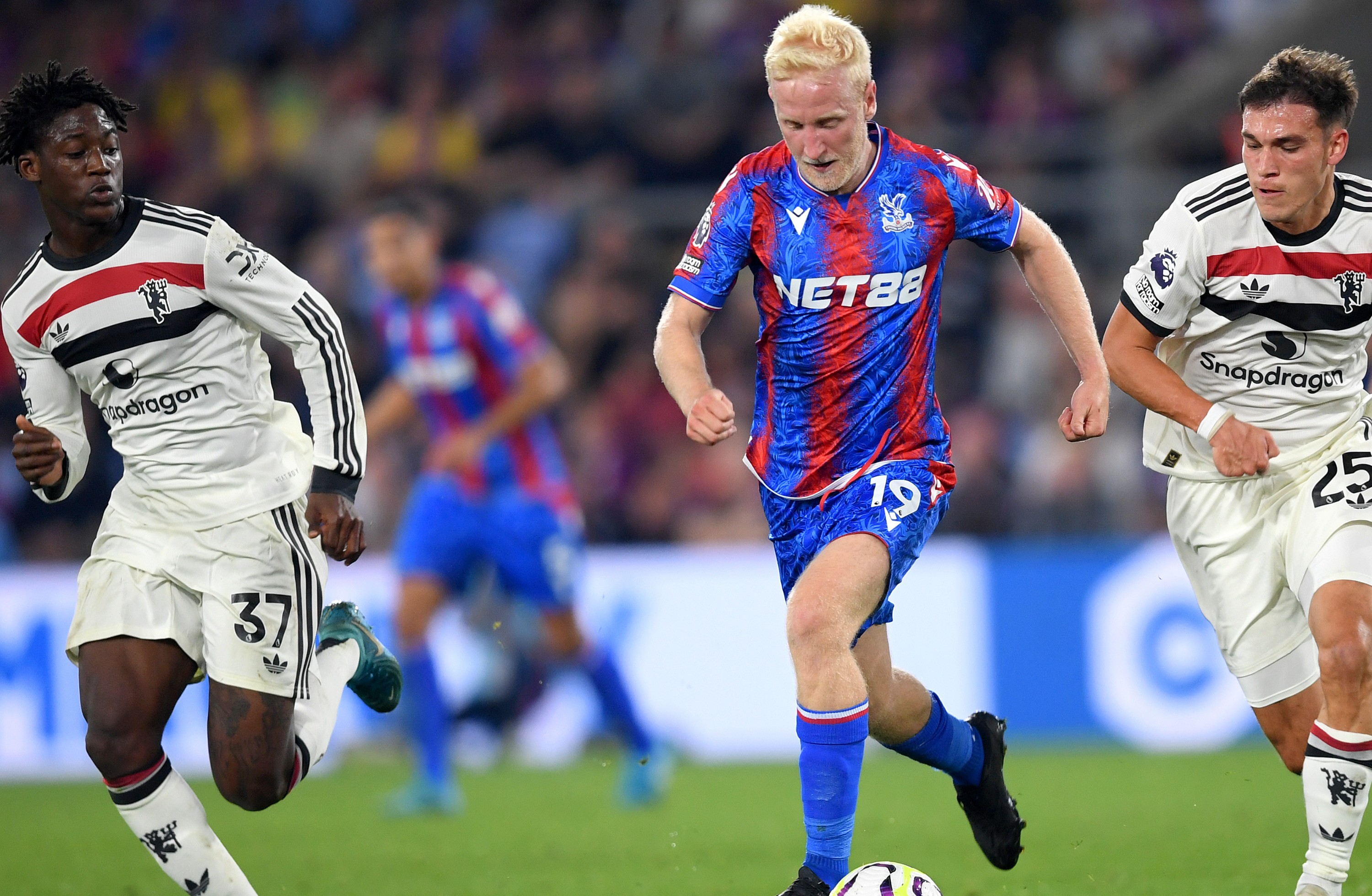 Will Hughes of Crystal Palace runs with the ball under pressure from Kobbie Mainoo and Manuel Ugarte of Manchester United