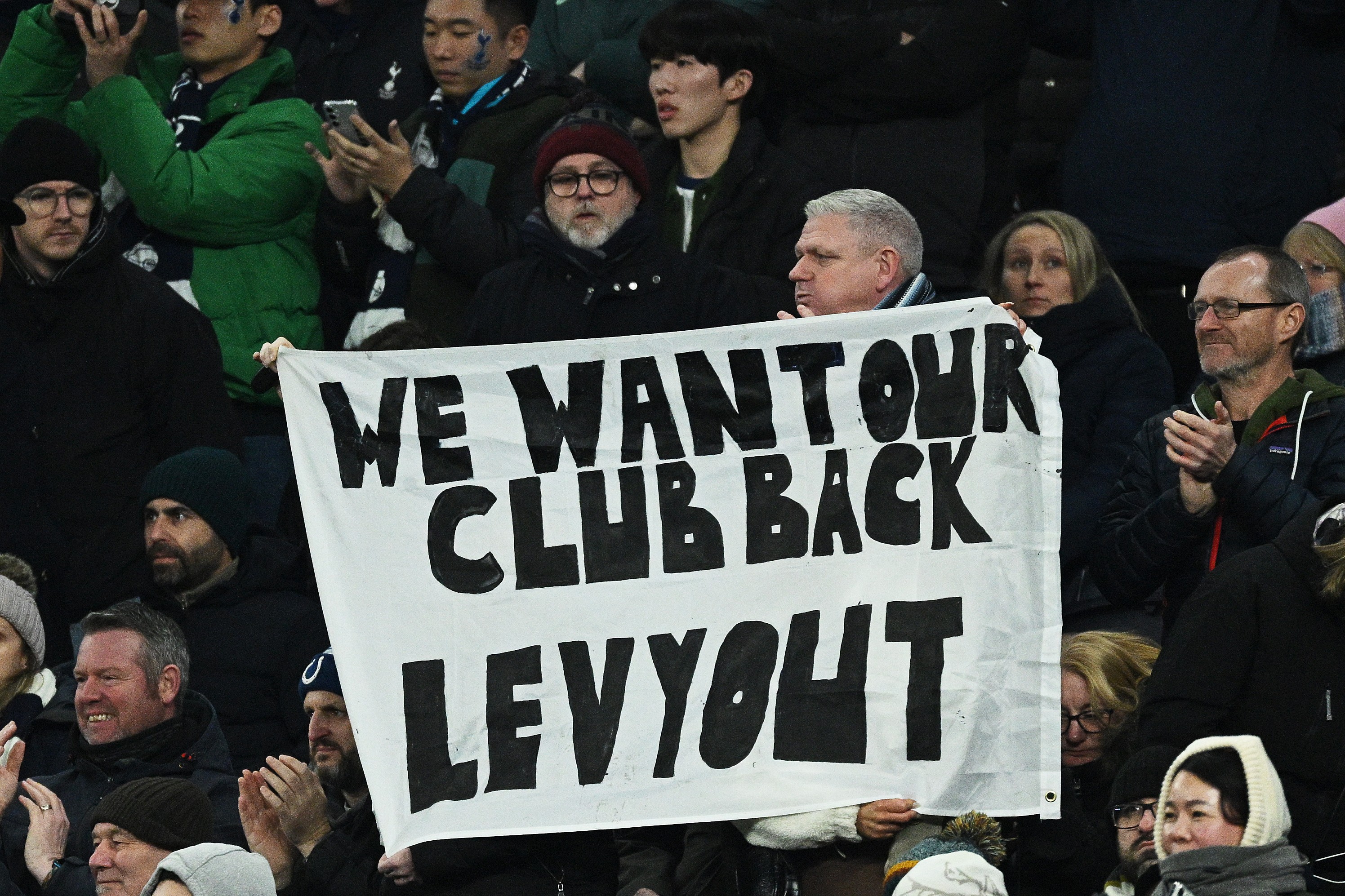 Fans of Tottenham Hotspur hold a banner which reads 'we want our club back Levy out'