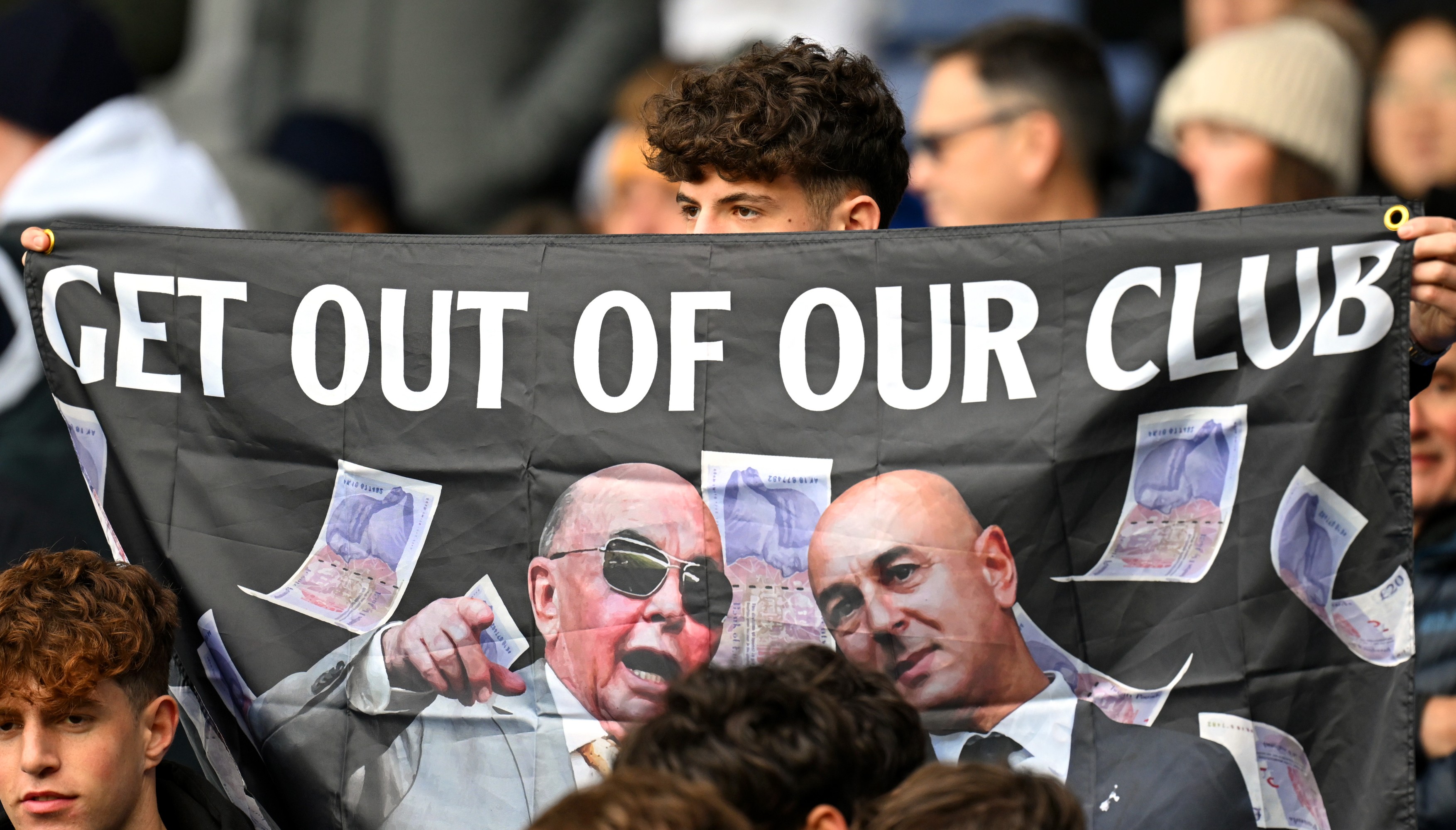 A fan of Tottenham Hotspur is seen with a flag which reads 'Get out of our club' with a picture of Daniel Levy