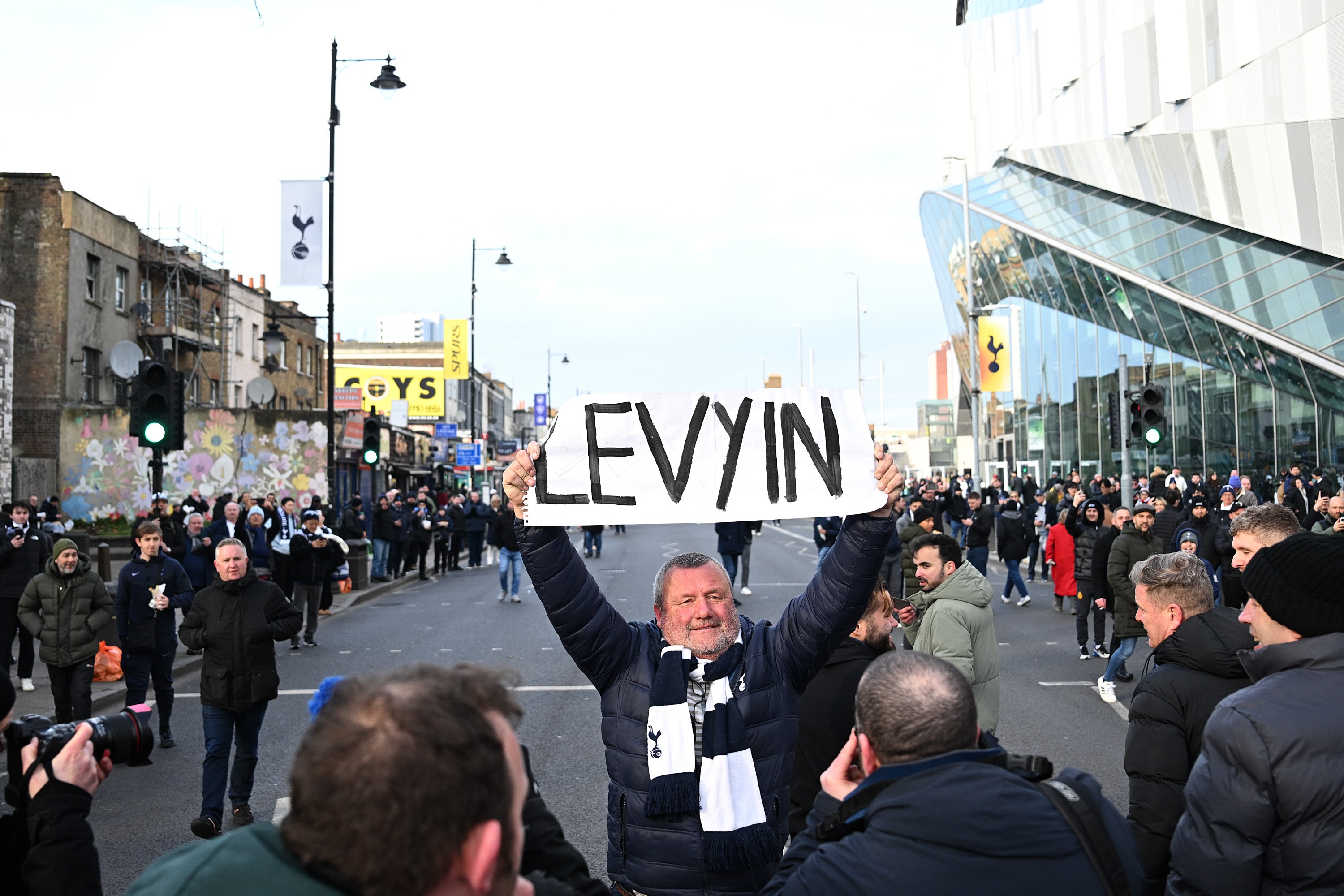 A fan of Tottenham Hotspur holds a protest banner outside the stadium in reference to Daniel Levy