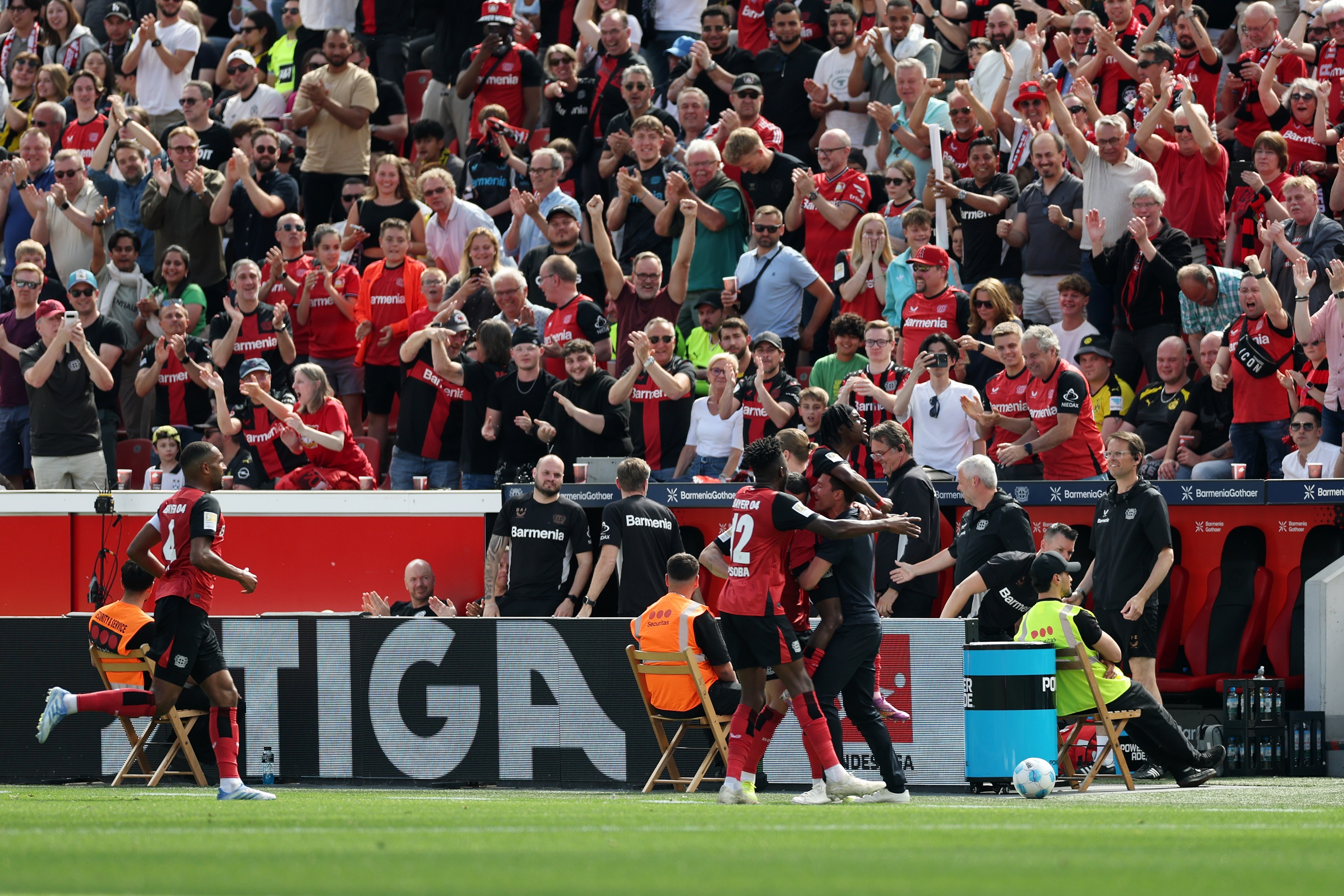 Jeremie Frimpong embraces Leverkusen's manager, Xabi Alonso, on the contact line against fans.