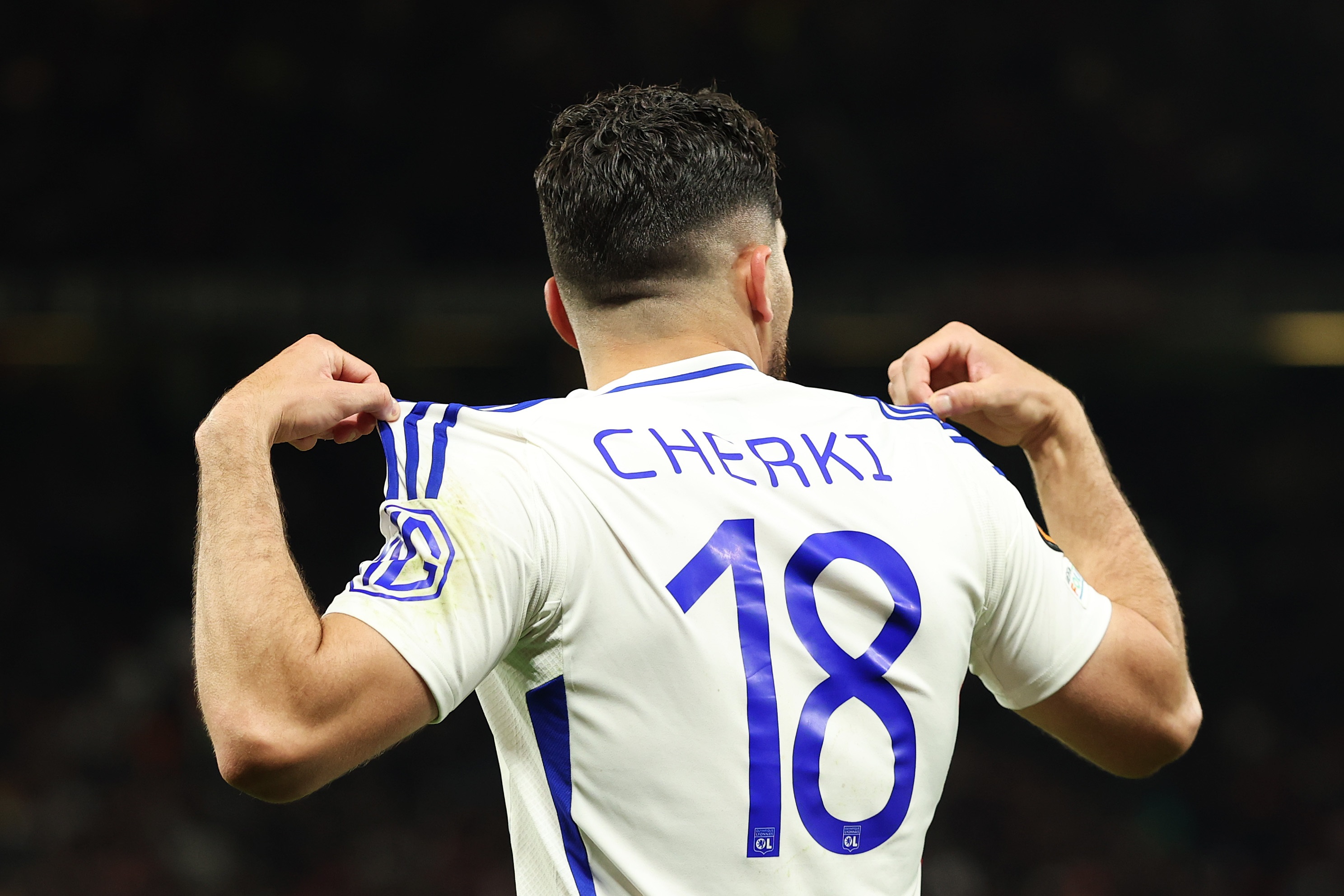 Rayan Cherki holds up the back of his shirt.
