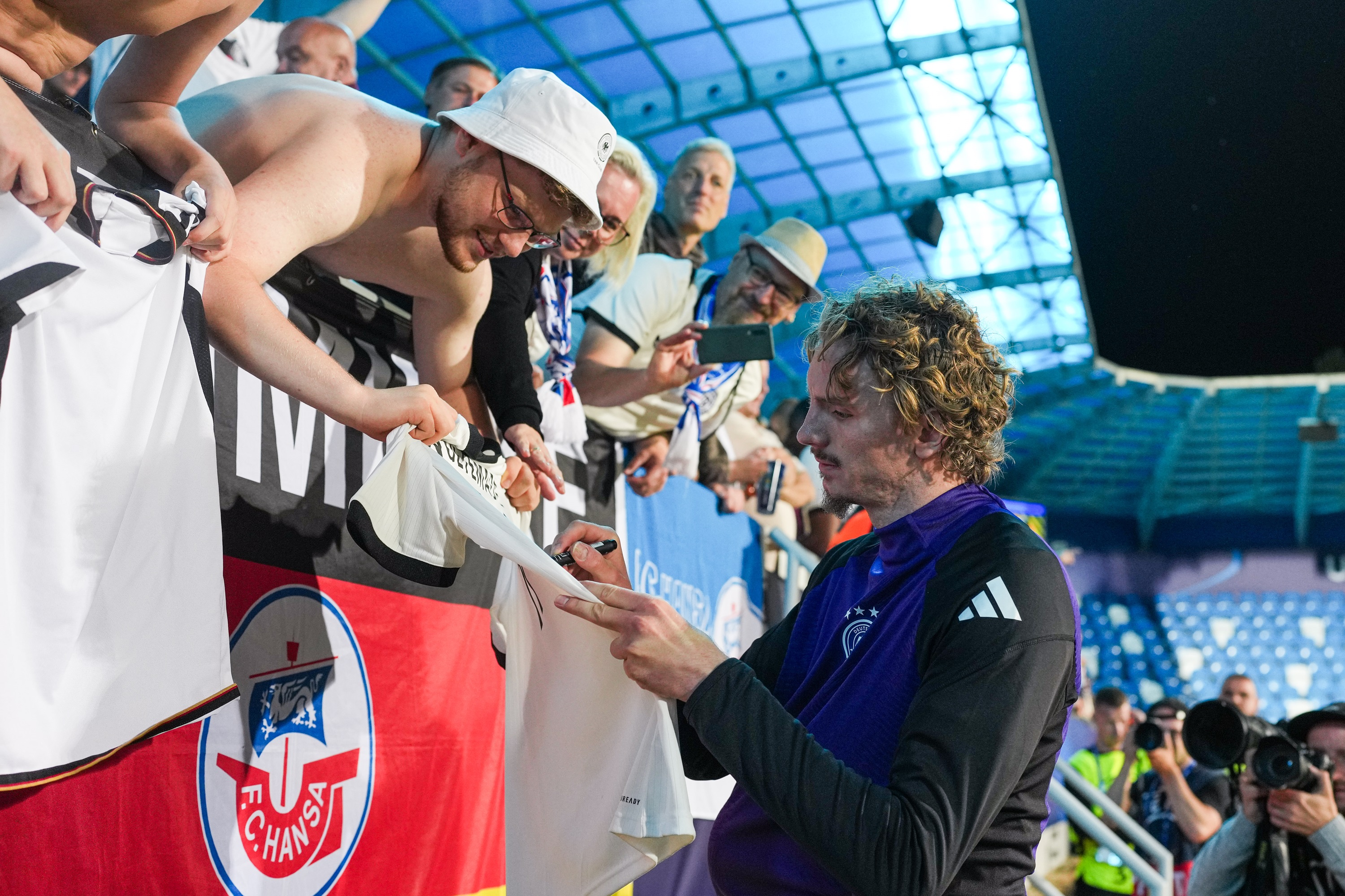 Nick Woltemade autographs a Germany fan's football shirt.