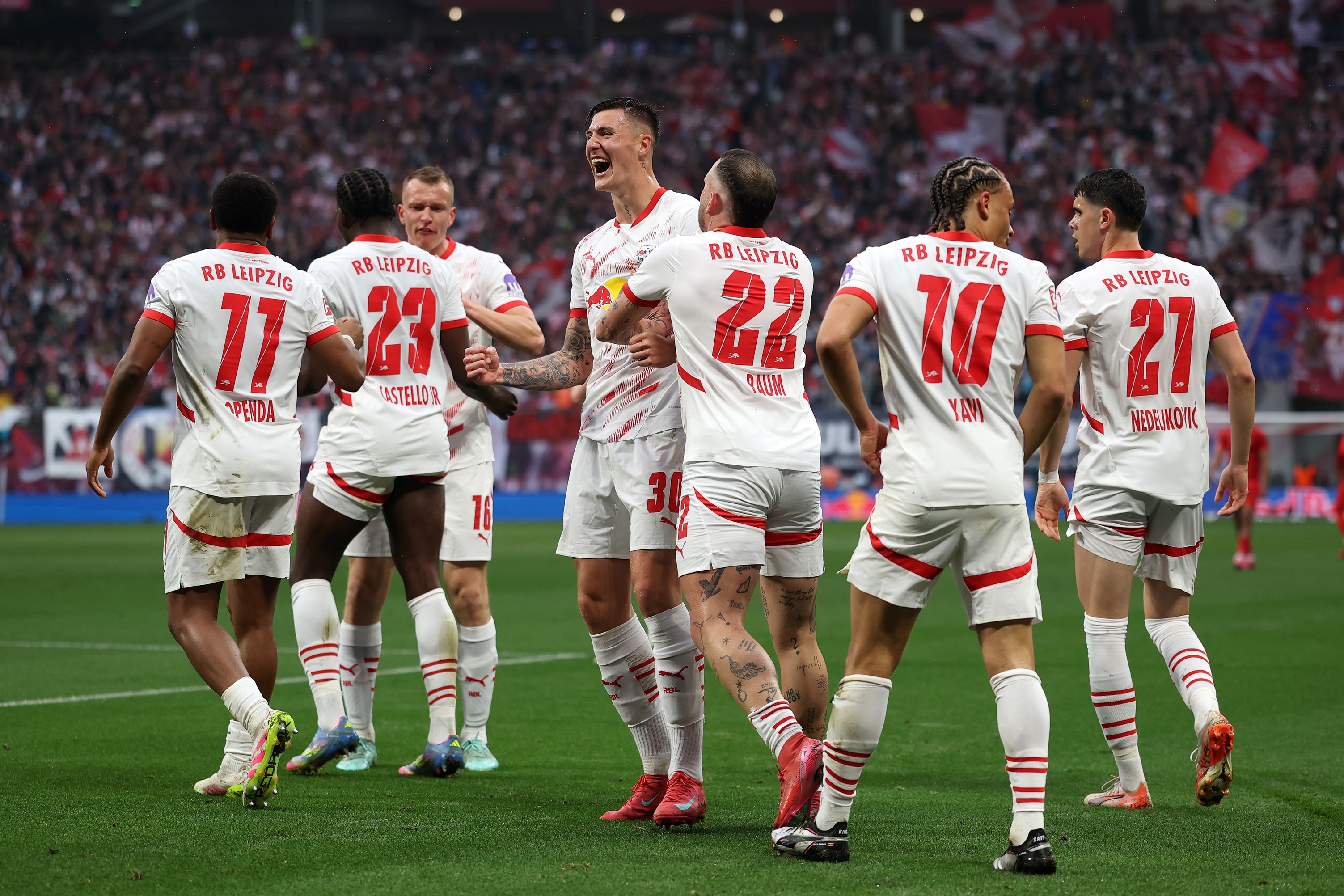 Benjamin Sesko is surrounded by RB Leipzig teammates during goal celebration.