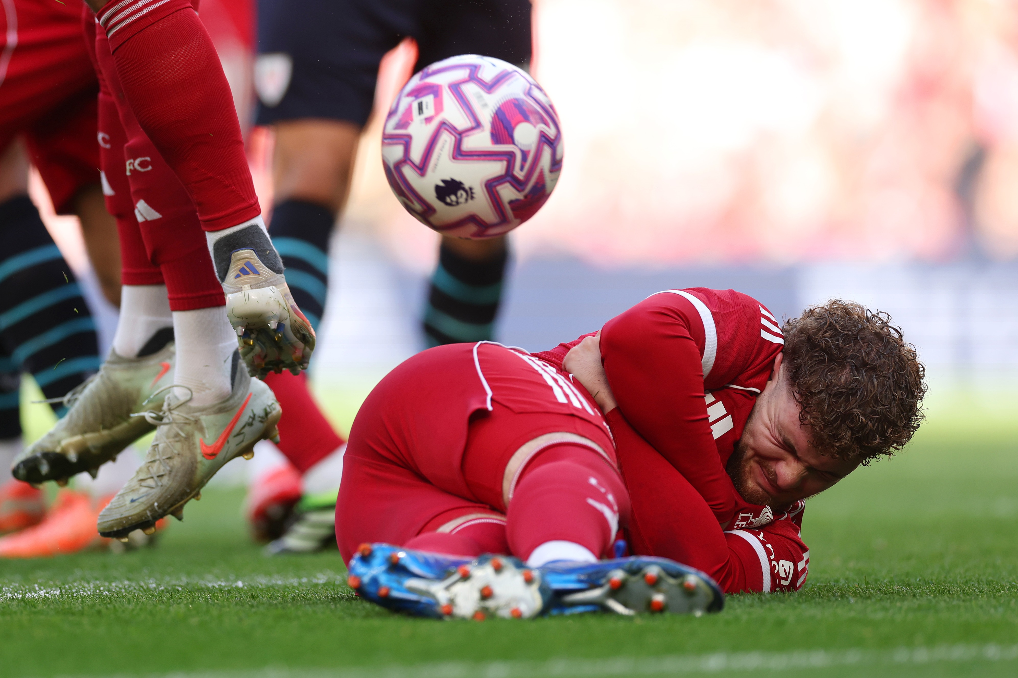 Harvey Elliott winces as he lies on the floor behind a wall of players.