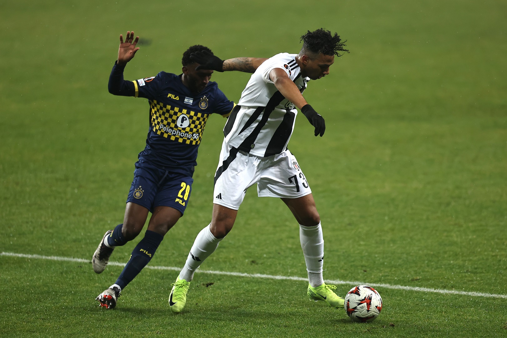 Cher Ndour of Besiktas runs with the ball whilst under pressure from Issouf Sissokho of Maccabi Tel-Aviv FC