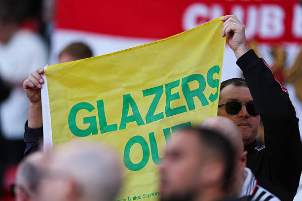 Manchester United fans protesting against the Glazers holding a Glazers Out banner.
