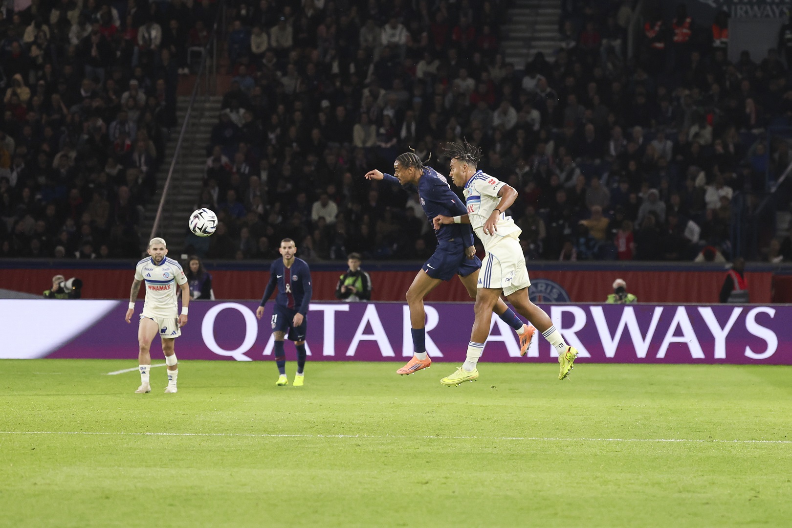 Bradley Barcola of Paris Saint-Germain jumps for the ball with a header against Guela Doue of RC Strasbourg