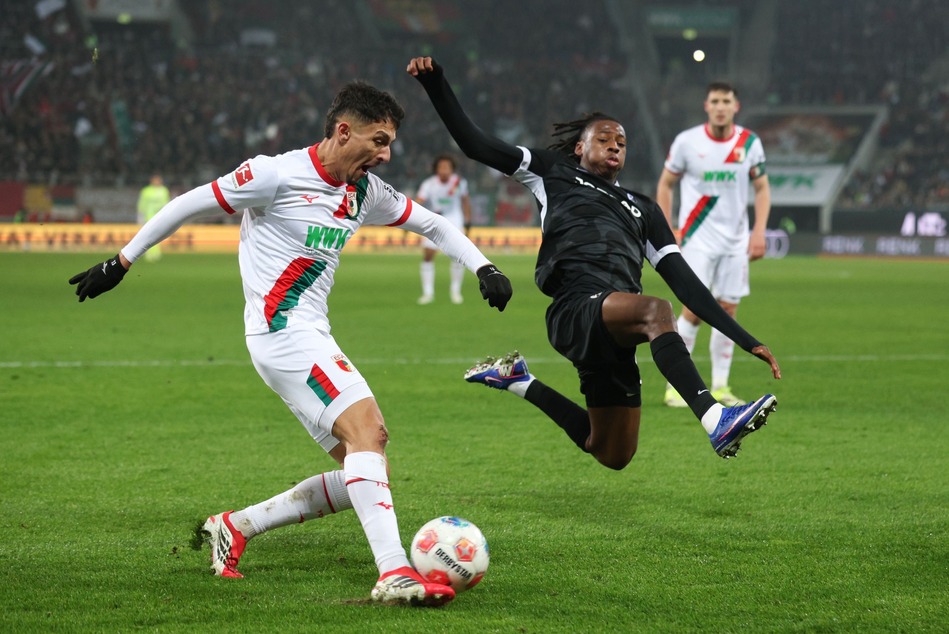 Johan Manzambi of Freiburg challenges Dimitris Giannoulis of Augsburg